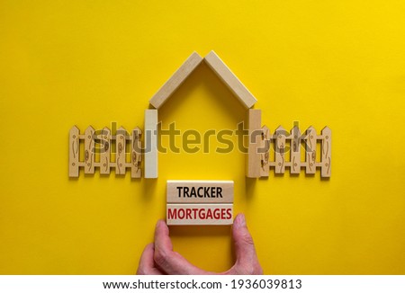 Tracker mortgage symbol. Concept words 'Tracker mortgage' on wooden blocks on a beautiful yellow backgrounds. Businessman hand. House model and wooden fence. Business, tracker mortgage concept.