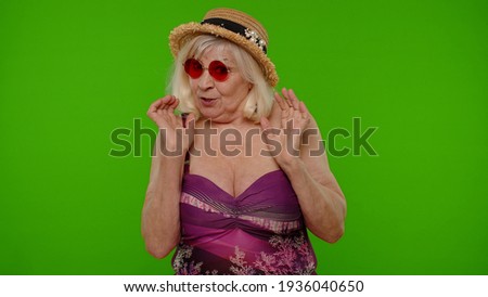 Scared elderly woman tourist stretching out hands, stop gesture to hide from fear, looking terrified afraid, panic attack on chroma key. Travel, summer holiday vacation. Senior grandmother in swimsuit