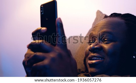 Man relaxing in the couch and browsing dating site on his smartphone. High quality photo