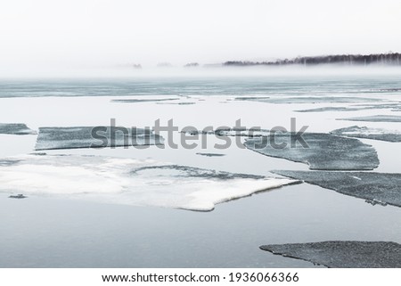 Melting ice on the shore of lake in misty morning. Beautiful spring landscape.