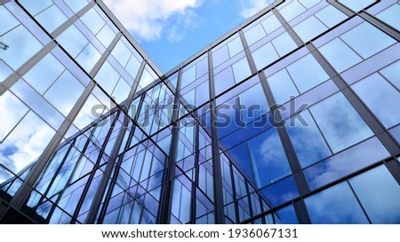 Modern office building with glass facade on a clear sky background. Transparent glass wall of office building. Royalty-Free Stock Photo #1936067131