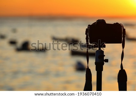 Camera on tripod take photo from sunrise over sea
