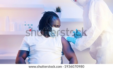 Unrecognizable doctor pressing cotton pad on top of shoulder of patient and making vaccine injection. Covid-19 protection. High quality photo