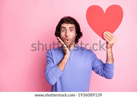 Photo of impressed person arm on cheek open mouth hold heart symbol isolated on pink color background