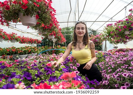  Portrait of beautiful woman in greenhouse between colorful flowers. Lifestyle