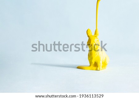 Yellow Easter bunny in paint on a blue background. Modern easter concept, copy space. Minimal creative postcard layout.