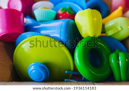 Plastic children's multi-colored dishes and vegetables, fruits for babies close-up in a paper box. Photography, concept.