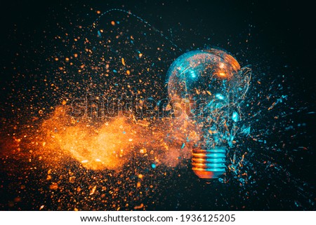 explosion of a filament light bulb. black background and blue and orange tones. high speed photography. Royalty-Free Stock Photo #1936125205