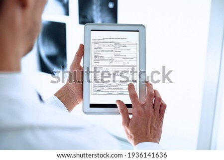 doctor is using a digital tablet to fill out the registration form. Royalty-Free Stock Photo #1936141636