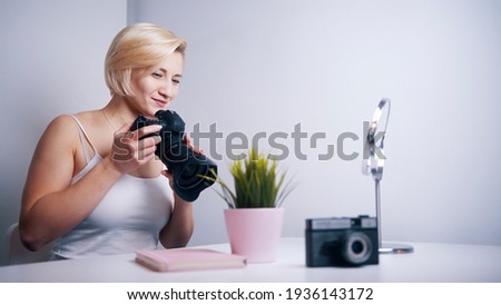 Happy young freelance photographer photographing plant in her home. High quality photo