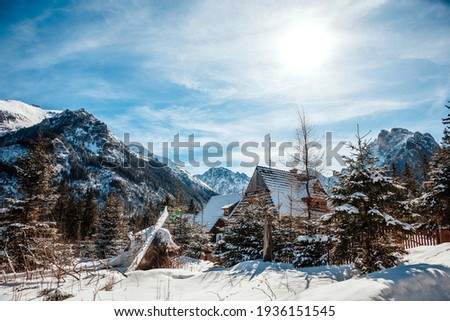 Standing one wooden house, in the morning sun on the road to Morskie Oko in the Tatras, among snowy mountains and tall trees