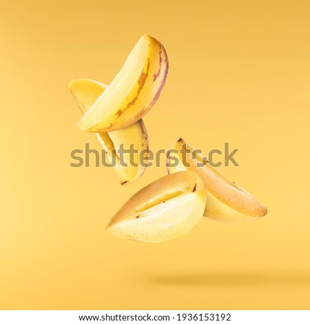 Fresh raw pepino dulce or sweet cucumber falling in the air isolated on yellow illuminating background. Food levitation concept. High resolution image