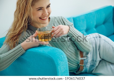 A woman at home is drinking tea on the couch. High quality photo.