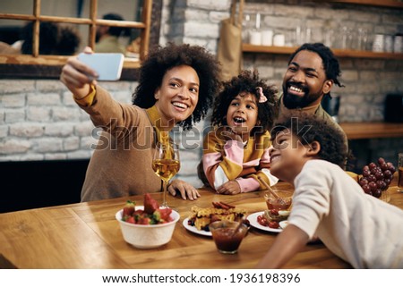 Happy black family having fun while taking selfie at home. 
