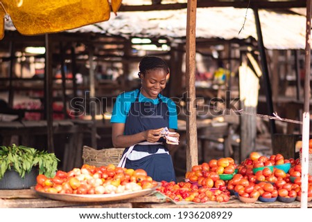 african market woman smiling while counting money Royalty-Free Stock Photo #1936208929