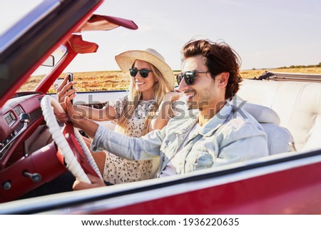 Woman taking a selfie during a road trip with boyfriend                               