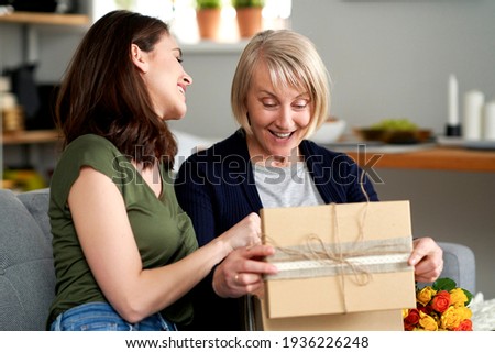 Happy mother unwrapping a gift from her adult daughter                               