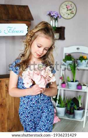 Beautiful blonde girl with bouquet of pink flowers on background of decorated flower shop. Easter, flower business concept