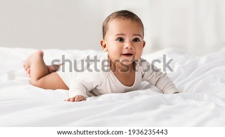 Cute little African American baby lying on bed at home