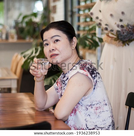 Happy beautiful woman to drinking water . Smiling asian female holding transparent glass in her hand .Focus at face , drinking water glass concept.

