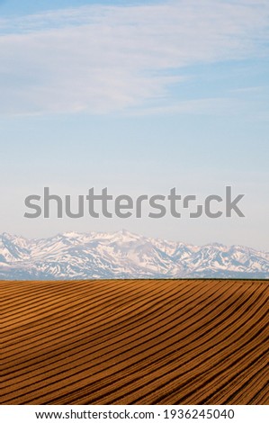 Plowed spring fields and snowy mountains
