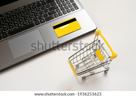 Laptop, shopping trolley, yellow credit card on a white background. Concept for online shopping, home delivery, black friday, discount. top view. Flat lay. copy space