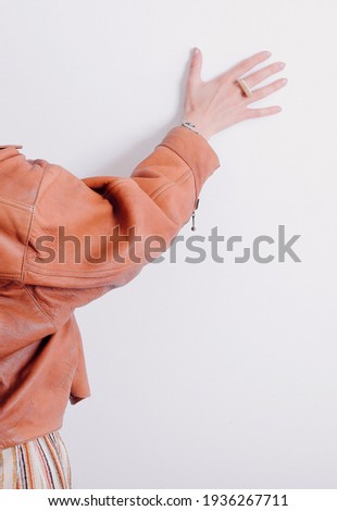 Girl female hand against the white wall with jewelry ring design presentation wearing a leather jacket