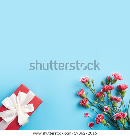 Concept of Mother's day holiday greeting gift design with carnation bouquet on bright blue table background