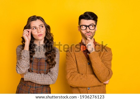 Portrait of attractive puzzled discontent couple touching specs overthinking solution isolated on bright yellow color background