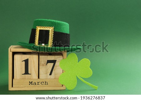 Leprechaun's hat, block calendar and St. Patrick's day decor on green background. Space for text