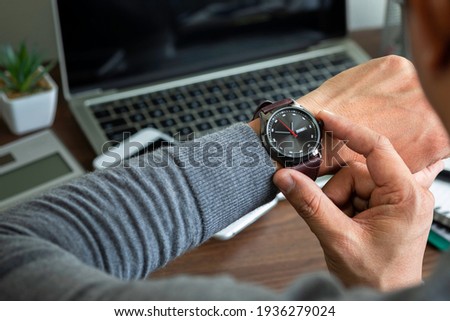 Close-up image of fashion luxury brown watch on wrist of man. Businessman working with laptop on desk office. Watching and checking the time on his wrist watch, a clock on his hands.