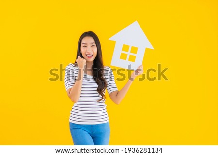 Portrait beautiful young asian woman show home sign paper on yellow isolated background