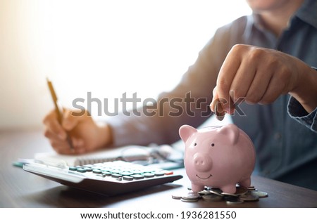 Close-up image of man hand putting coins in pink piggy bank for account save money. Planning step up, saving money for future plan, retirement fund. Business investment-finance accounting concept. Royalty-Free Stock Photo #1936281550
