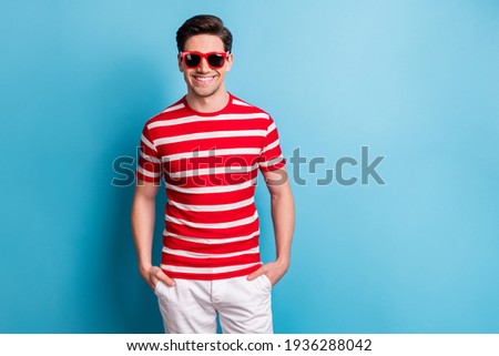 Photo portrait of young man smiling wearing stylish sunglass striped t-shirt shots isolated on vivid blue color background blank space