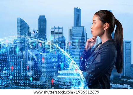 Attractive young Asian HR director at international company is thinking about recruitment of highly qualified specialists. Women in business concept. Social media hologram icons over Singapore.