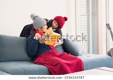 Asian man and woman couple family in casual outfit holiday winter theme giving gift for special day with happy and romantic in modern living room