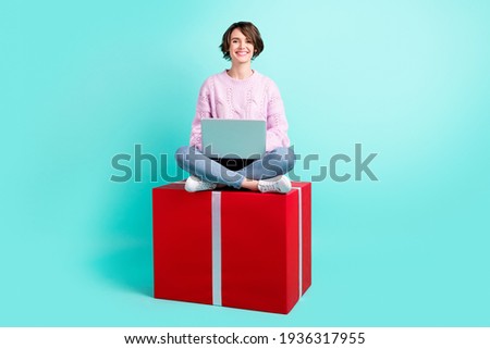 Photo of sweet impressed young lady dressed purple pullover sitting red present writing modern device isolated teal color background