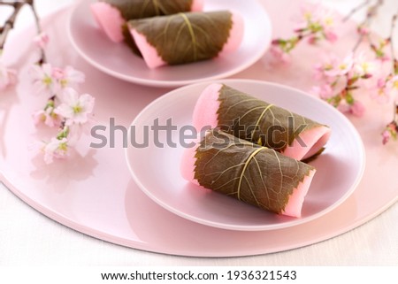 Japanese traditional sweets, 
Sakura Mochi wrapped with salted cherry leaves.
Beautiful cherry blossoms background. 