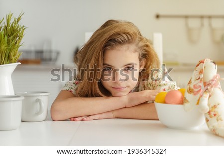  white european girl 10 years old in the kitchen at the table with Easter eggs 