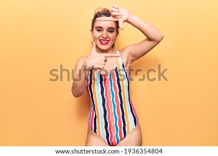 Young beautiful blonde woman wearing swimwear smiling making frame with hands and fingers with happy face. creativity and photography concept. 
