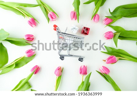 spring flat lay with gifts, tulips and shopping cart on table.
