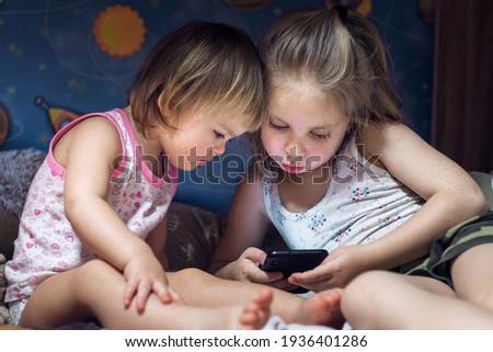 sisters on bed looking at smartphone. technological concept