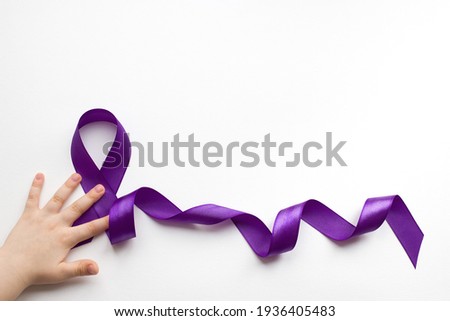 Purple ribbon with a child's hand on a white background with a place for text in honor of the day of patients with epilepsy on March 26 Royalty-Free Stock Photo #1936405483