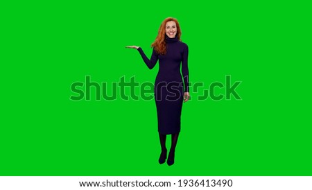 Charming elegant red headed business woman in long dress doing presentation and gesturing on green screen background
