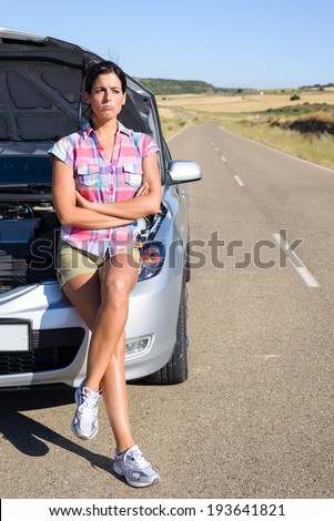 Upset sad woman waiting for road service help after car accident or engine breakdown. Roadtrip vacation problem concept.