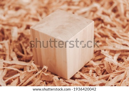 One wooden block on a background of carpentry shavings. Copy, empty space for text.