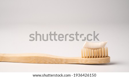 Eco dental concept. Natural toothpaste on a bamboo toothbrush. Wooden toothbrush on white background with copy space Royalty-Free Stock Photo #1936426150