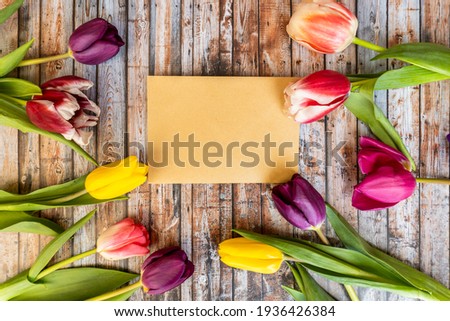 Spring tulip flowers  on rustic background, top view. Envelope, selective focus. Colorful tulips and vintage letters on wooden background. Copy space for text. Feminine concept.