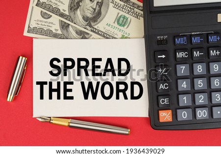 Business and finance concept. On a red background, among the money, a calculator and a pen lies a sign with the text - SPREAD THE WORD