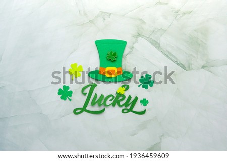 Green Hat with Lucky lettering decoration and cloverleafs. Saint Patricks day greeting card. Space for text. Soft focus. Top view.